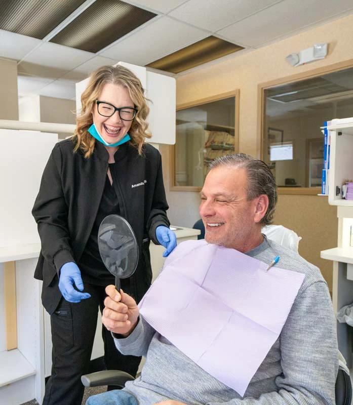 A female staff member with a patient in the exam room smiling while looking into a mirror at Family Dental Practice in Kokomo IN.