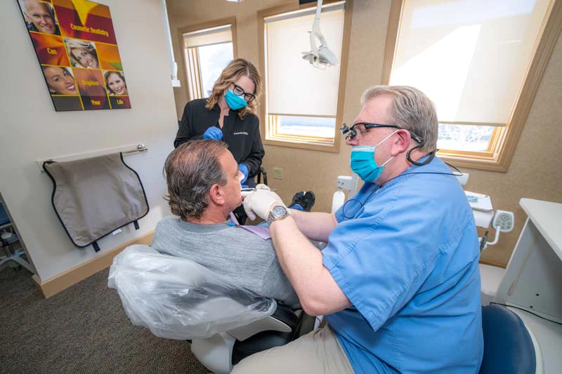 Dr. Kevin Welch looking at a patients teeth while discussing dental crown options at Family Dental Practice in Kokomo IN.