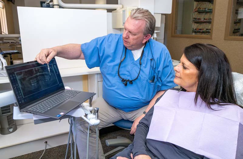 Dr Welch discussing sedation options with a patient while pointing at a computer screen at Family Dental Practice in Kokomo IN.